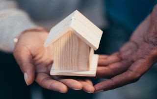 mains présentant une maison en bois